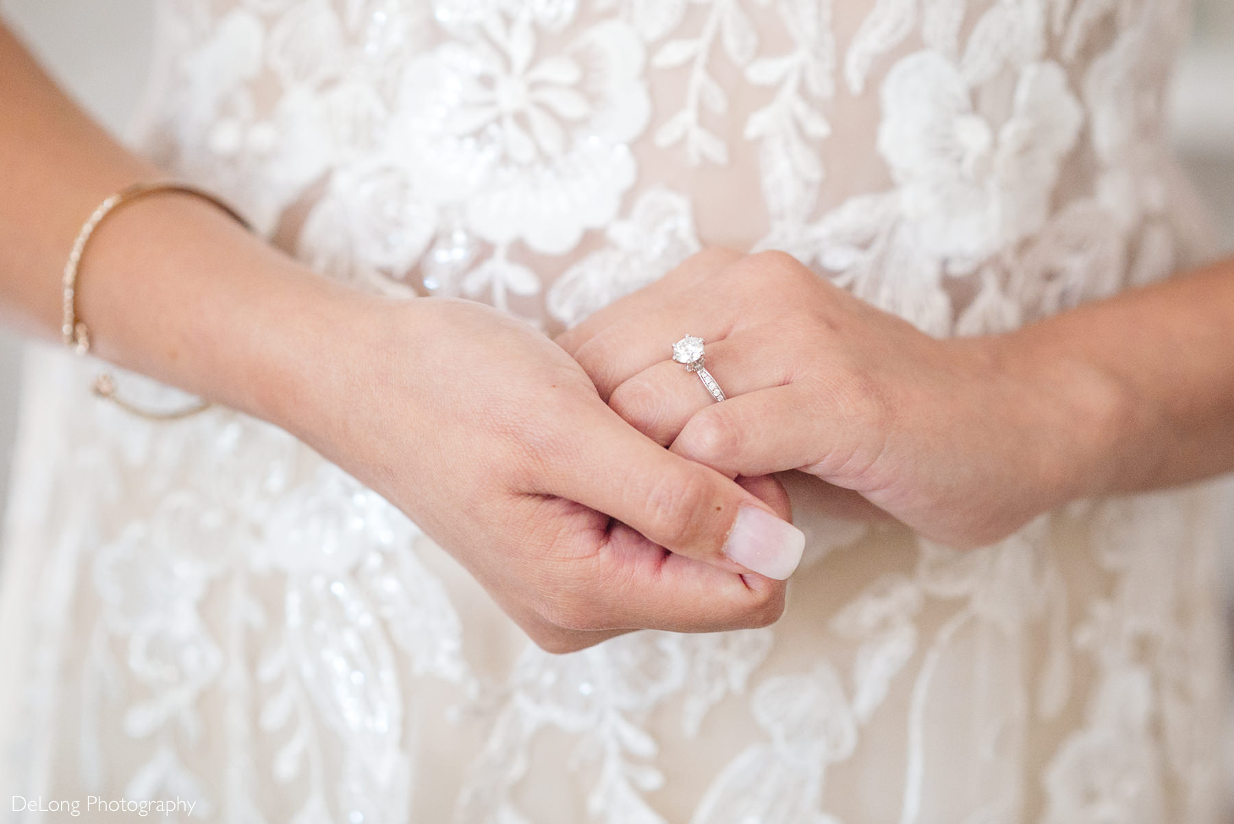 Close-up of bride’s hands showcasing her engagement ring and lace Áo Dài-inspired jumpsuit before her Raleigh courthouse elopement, photographed by DeLong Photography.