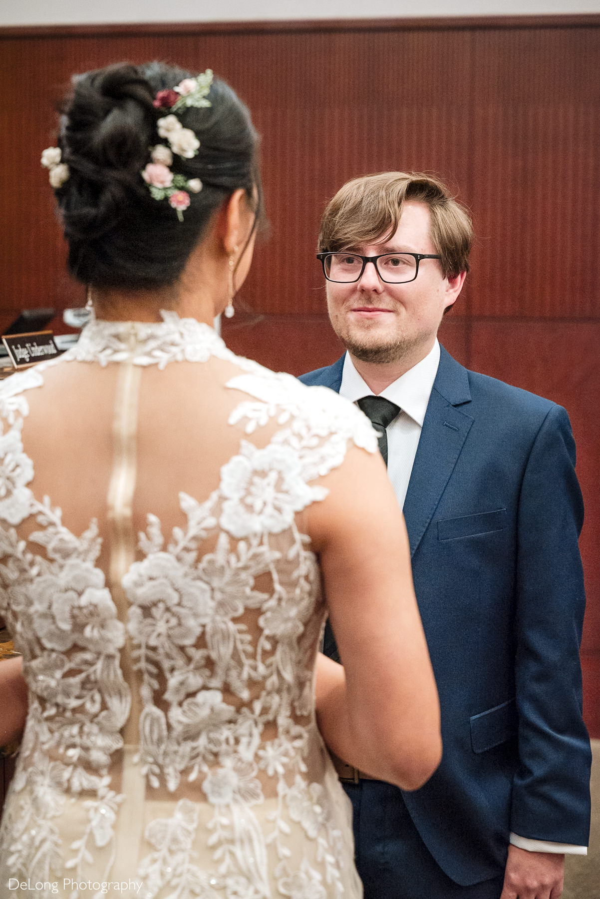 Groom gazes lovingly at his bride during their intimate Raleigh elopement ceremony at the Wake County Courthouse, captured by DeLong Photography.