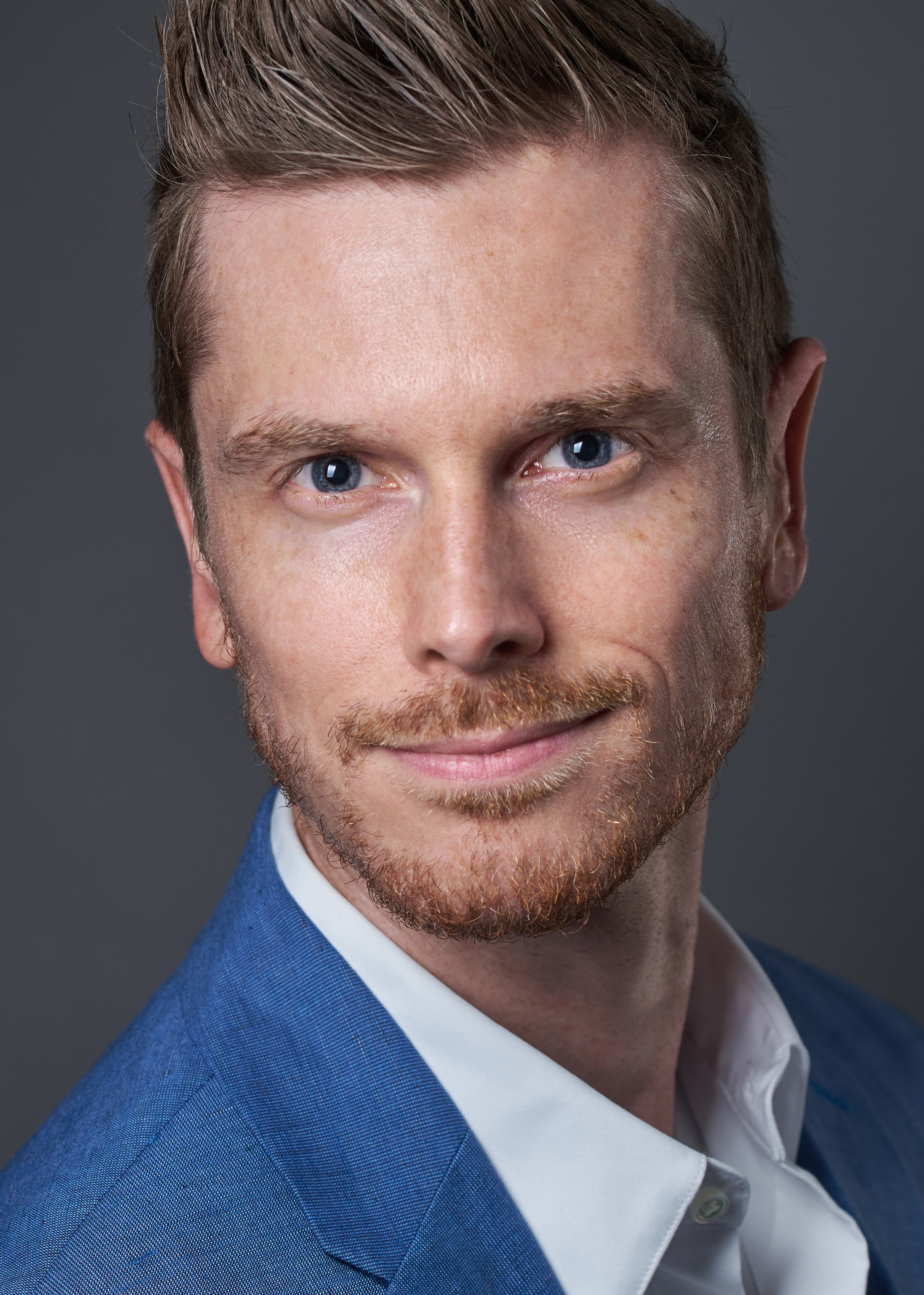 Professional Charlotte headshot photographer captures modern business portrait of man in business attire against dark grey background.