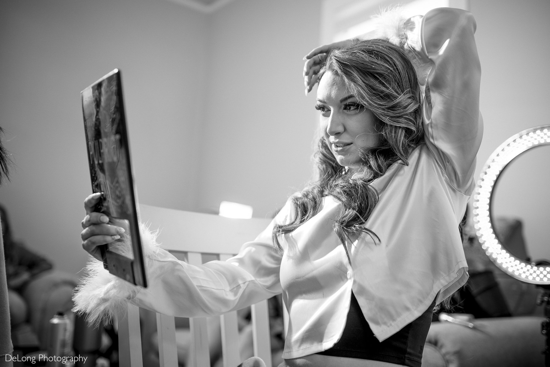 Bride checking her hair and makeup in the mirror while getting ready for her boho-glam wedding at The White Home in Rock Hill, SC. Black and white bridal preparation photo captured by DeLong Photography.