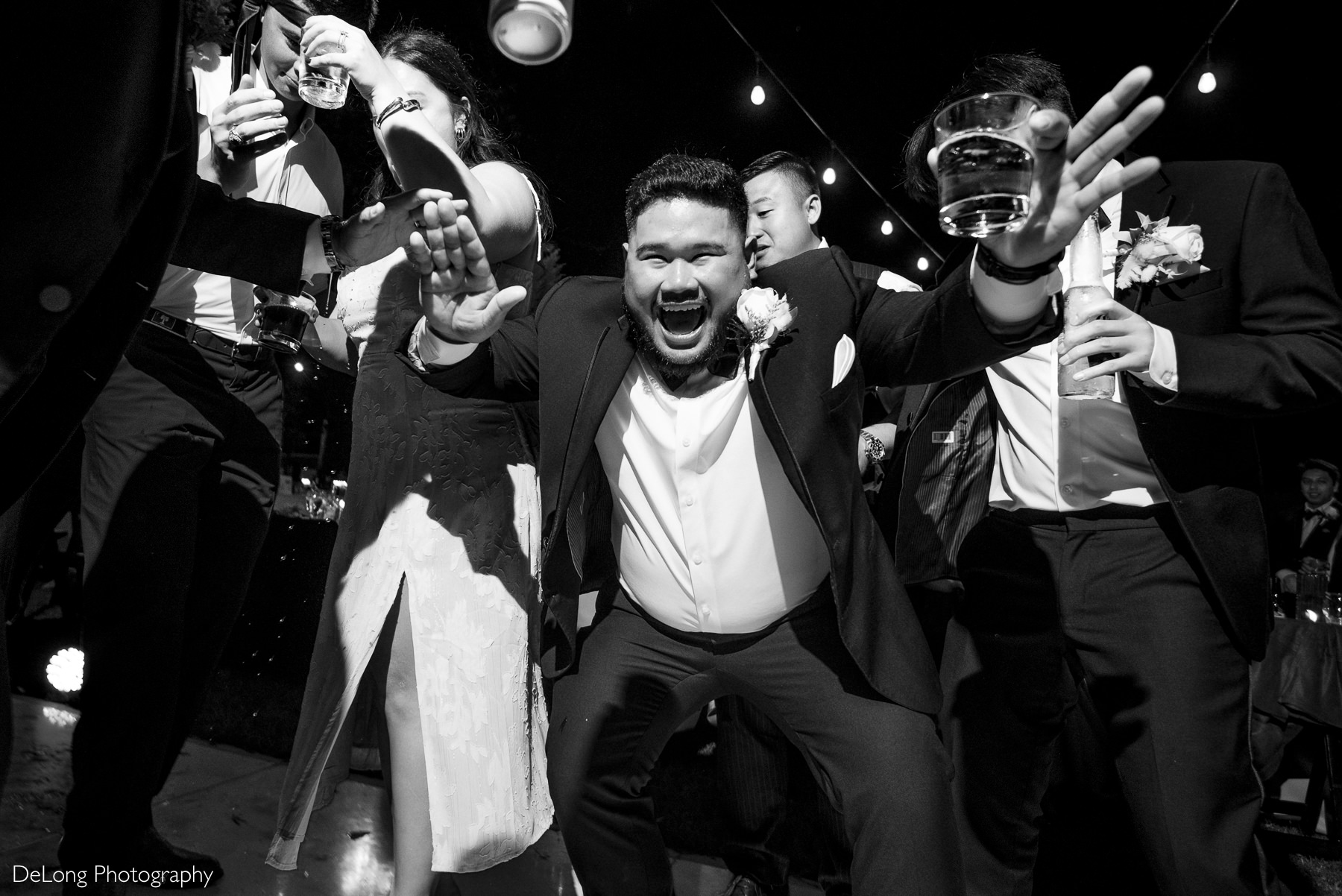 Wedding guests dance and cheer with drinks in hand during lively reception at The White Home in Rock Hill.