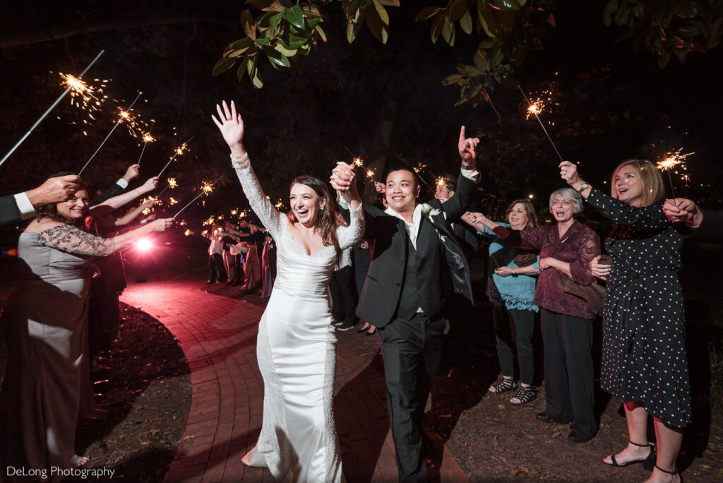 Bride and groom celebrate during a sparkler wedding exit at The White Home in Rock Hill, surrounded by cheering guests and glowing sparklers.