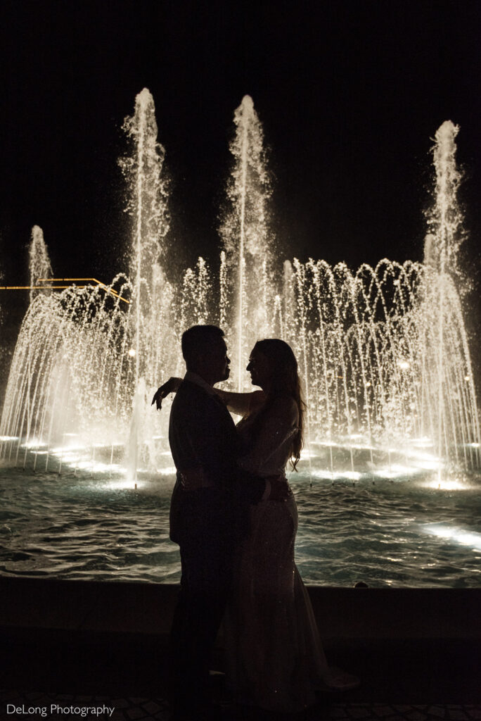 Bride and groom silhouette in front of illuminated fountain at night during their wedding in Rock Hill, South Carolina.
