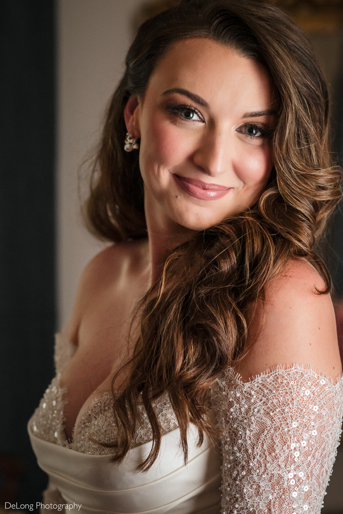 Bride with long wavy hair and natural glam makeup smiling in an off-the-shoulder lace wedding gown during her boho-glam wedding at The White Home in Rock Hill, SC. Bridal portrait by DeLong Photography.