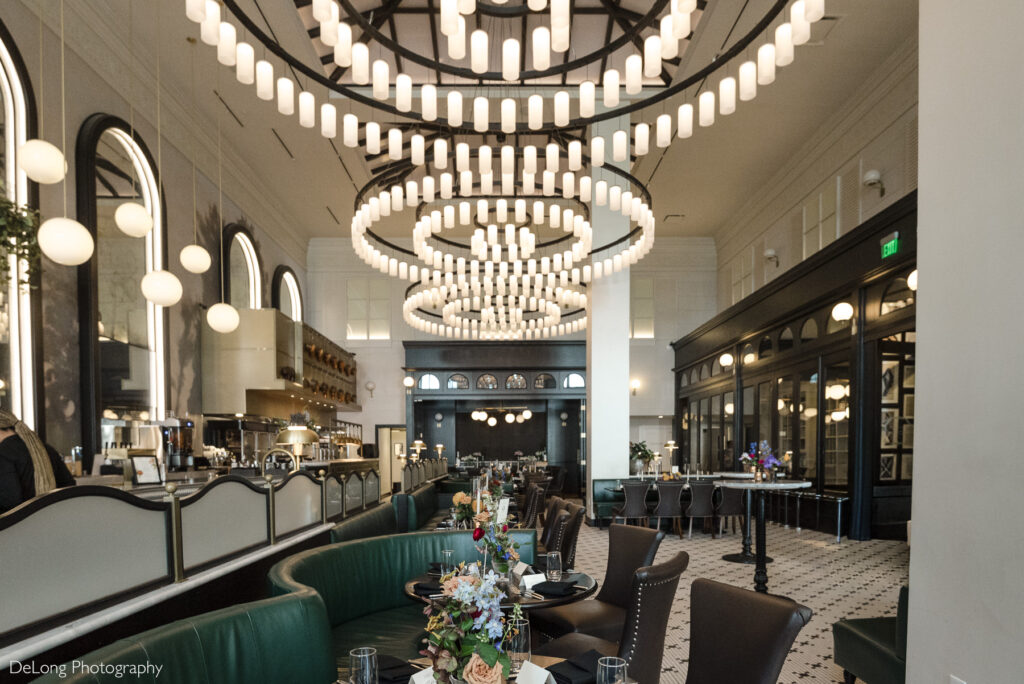 Interior of La Belle Helene in Charlotte, NC, featuring grand circular chandeliers, elegant brasserie décor, and beautifully set tables—an ideal restaurant venue for intimate wedding receptions and upscale celebration dinners.