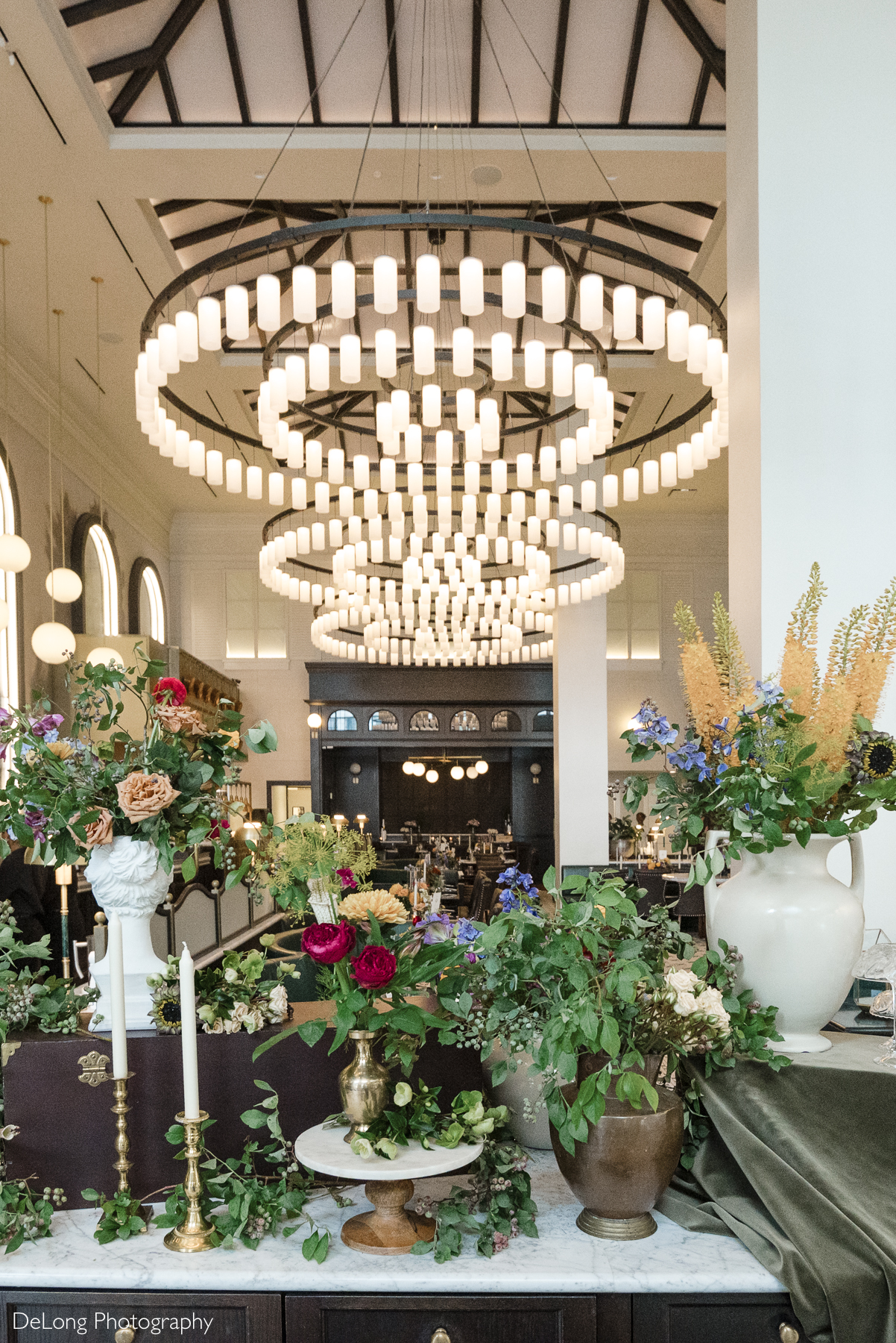 Floral décor inside La Belle Helene in Charlotte, NC, featuring lush wedding-style centerpieces and grand circular chandeliers—showcasing the restaurant’s elegant atmosphere for intimate wedding receptions.