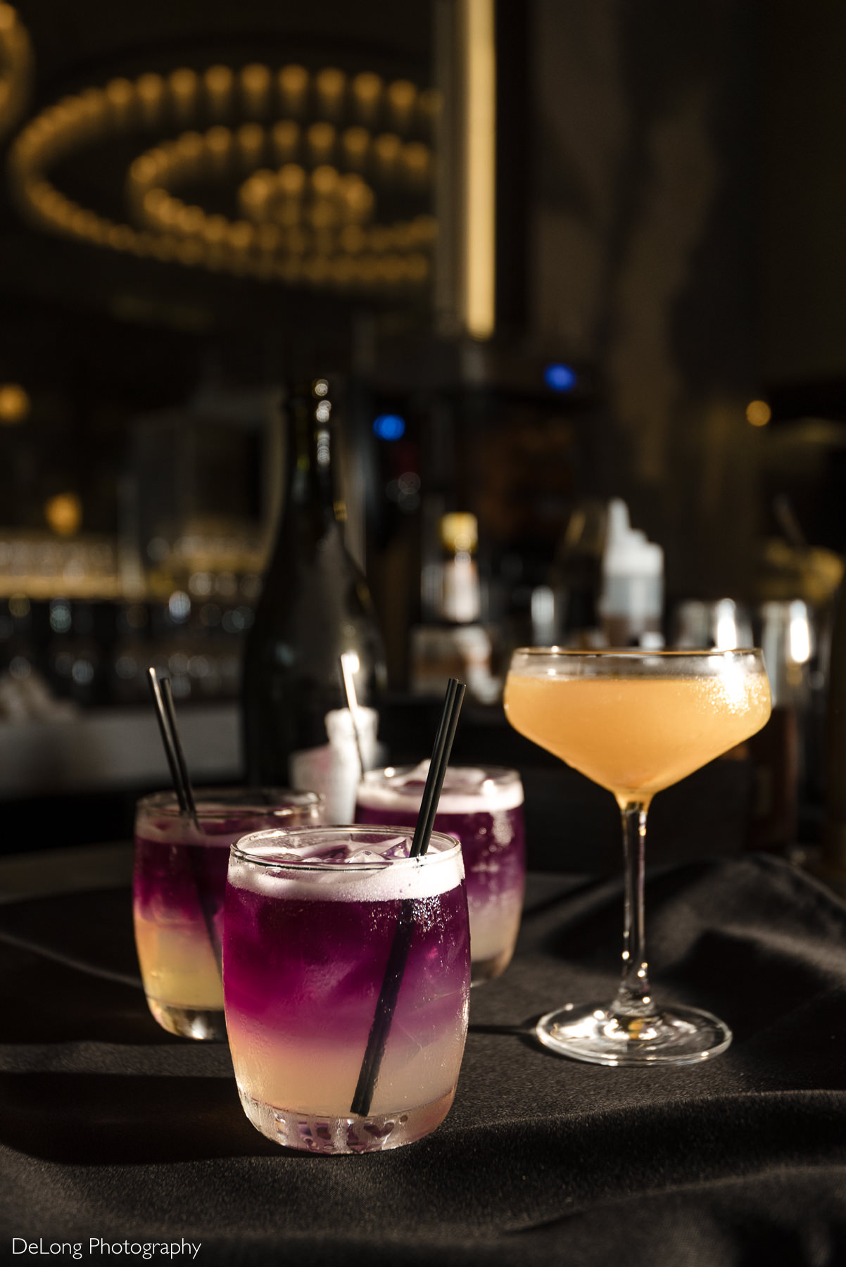 Craft cocktails displayed at La Belle Helene in Charlotte, NC, with elegant glassware and warm ambient lighting—highlighting the French brasserie’s refined bar experience for stylish wedding receptions and private events.