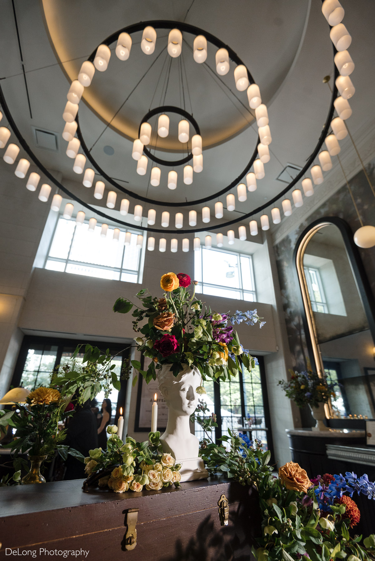 Floral centerpiece styled on a sculptural vase beneath La Belle Helene’s signature circular chandeliers in Charlotte, NC—showcasing the restaurant’s elegant, modern ambiance ideal for intimate wedding receptions.