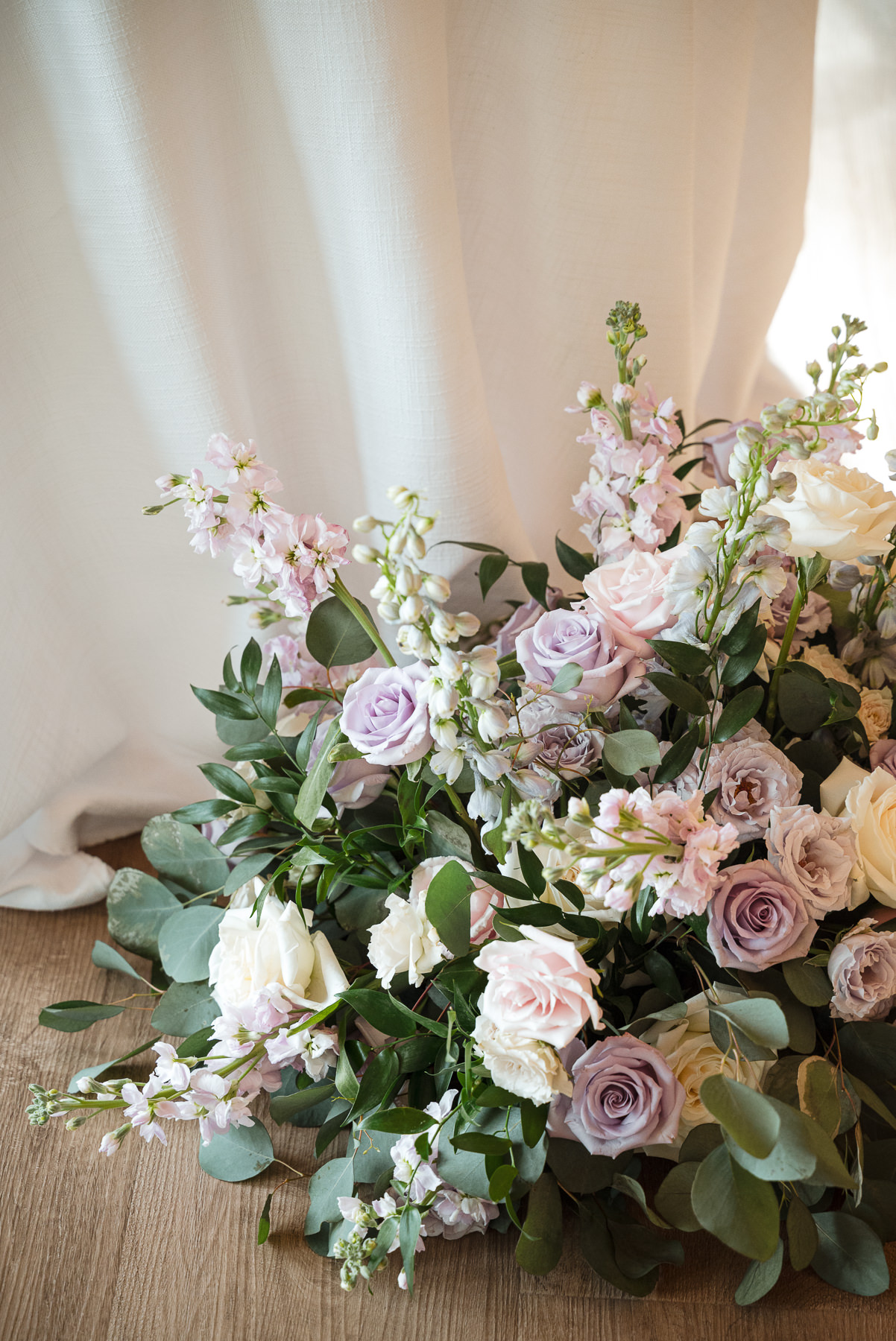 Pastel spring wedding bouquet with lavender and blush roses, white blooms, and eucalyptus greenery at Daniel Stowe Botanical Gardens in Belmont, NC, photographed by DeLong Photography.