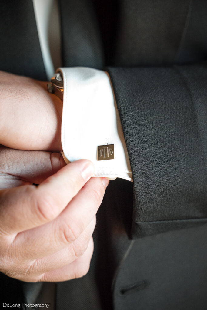 Close-up of groom adjusting monogrammed cufflinks while getting ready for a wedding at Childress Vineyards in Lexington, North Carolina.