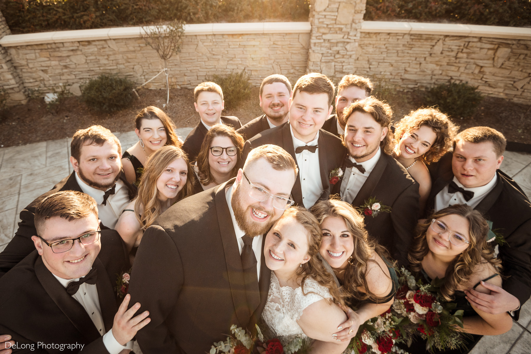 Wedding party group portrait at Childress Vineyards in Lexington, North Carolina, with the bride and groom surrounded by smiling bridesmaids and groomsmen in formal attire during golden hour.