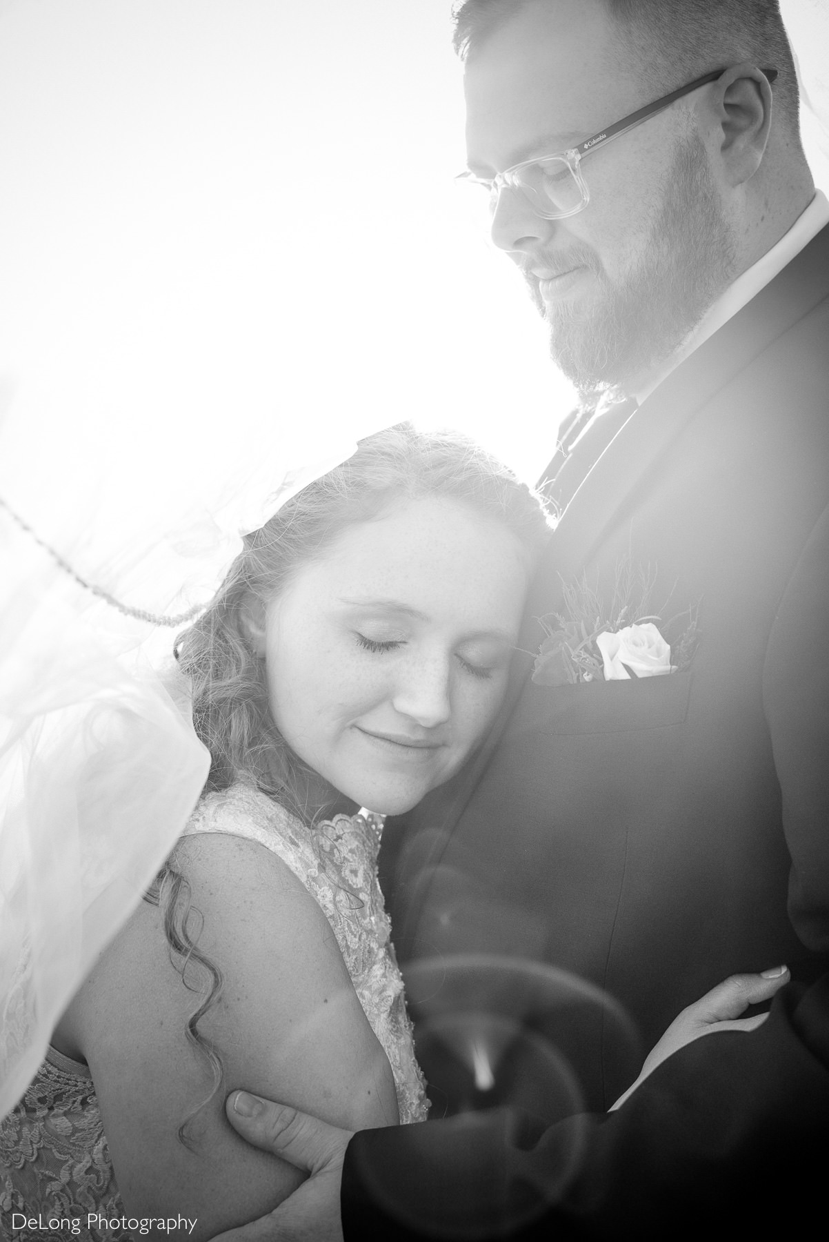 Black and white intimate wedding portrait at Childress Vineyards in Lexington, North Carolina, showing the bride resting her head against the groom’s chest in a quiet, emotional moment.