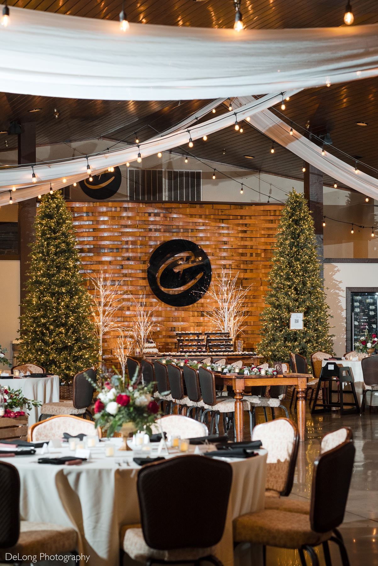 Elegant winter wedding reception space at Childress Vineyards in Lexington, North Carolina, featuring draped ceilings, café lights, and Christmas tree décor.