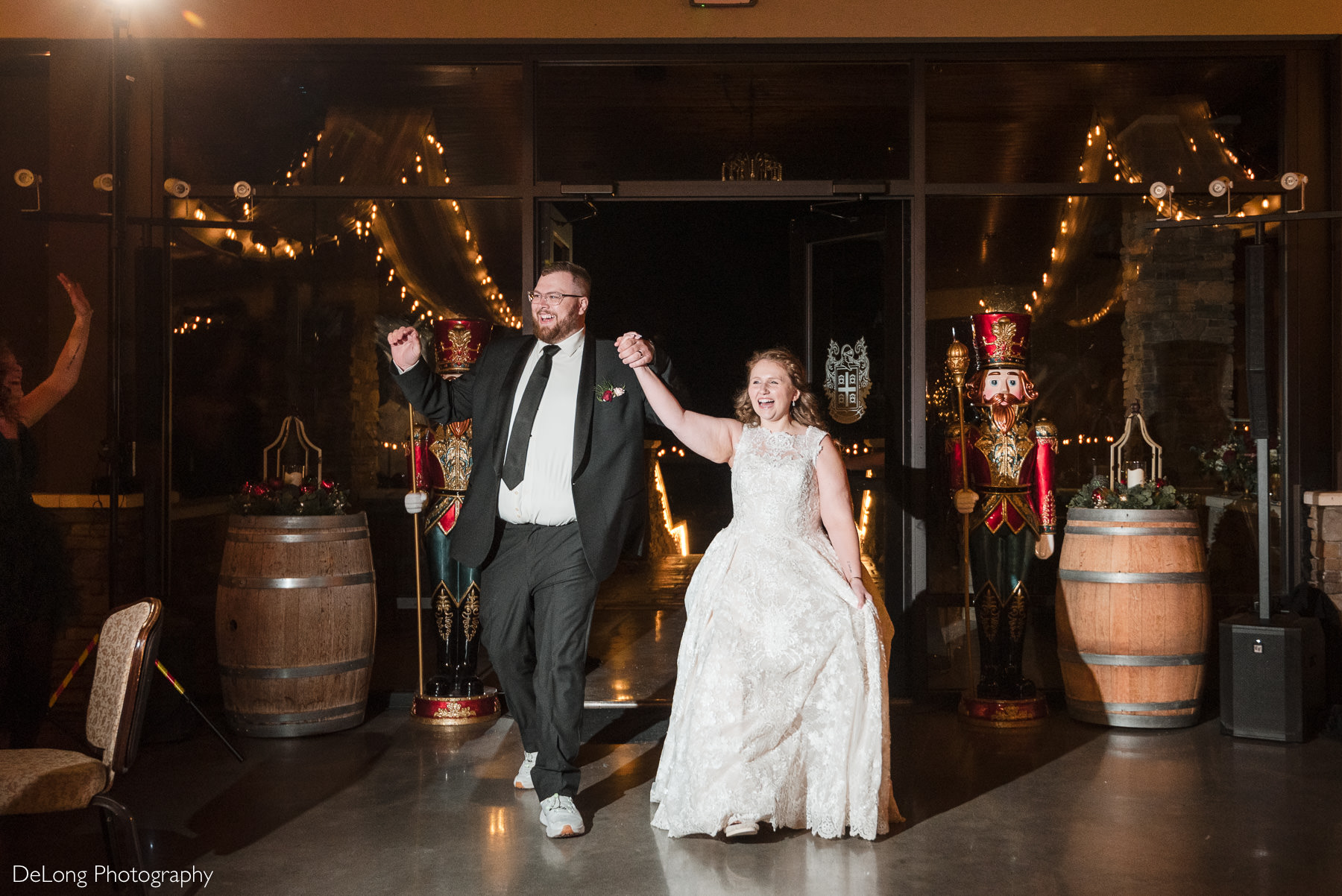 Bride and groom make a joyful reception exit at Childress Vineyards in Lexington, North Carolina, walking hand in hand between festive nutcracker statues during their winter wedding.