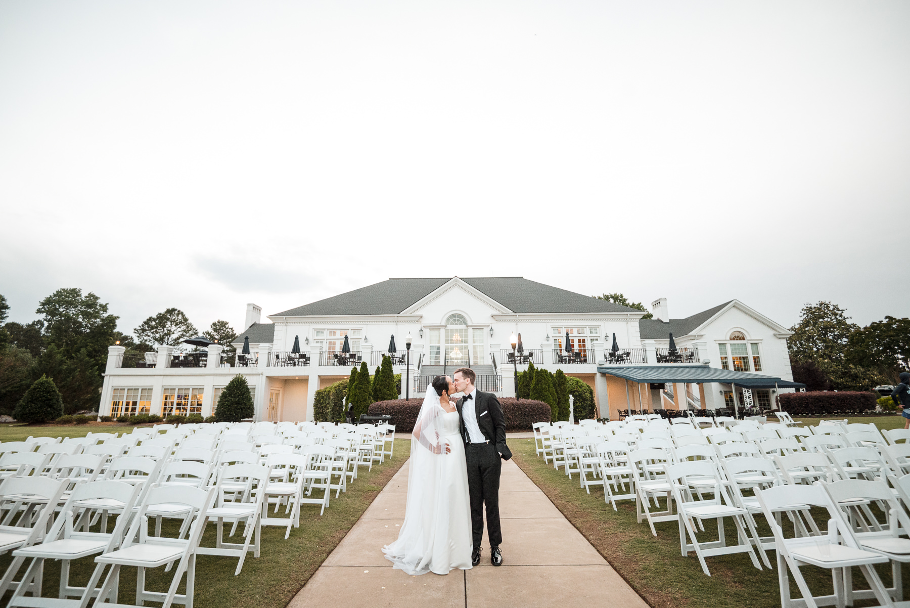 Bride and groom sharing a kiss after their outdoor wedding ceremony at Providence Country Club, photographed by DeLong Photography, a Charlotte wedding photographer specializing in elegant country club weddings, candid moments, and timeless wedding photography in Charlotte, NC.