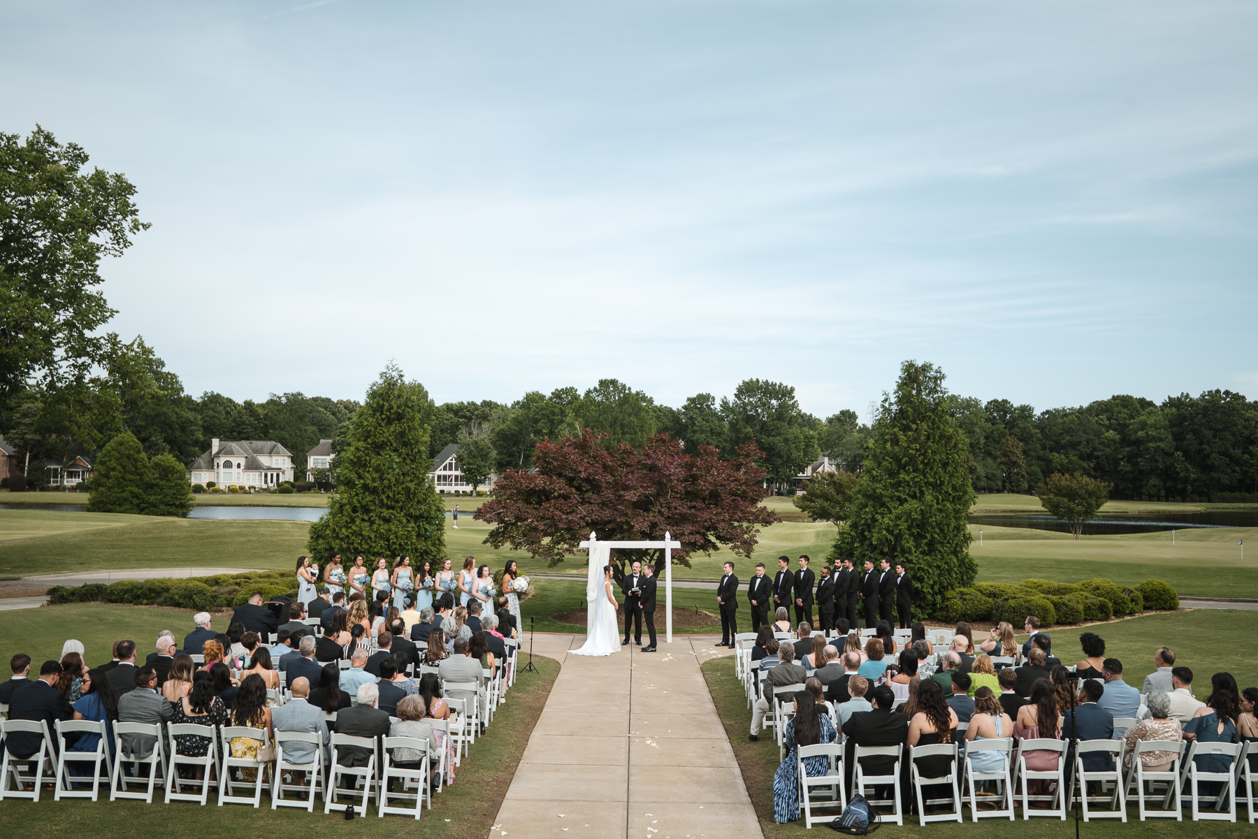 Wide view of an outdoor wedding ceremony at Providence Country Club overlooking the golf course, photographed by DeLong Photography, a Charlotte wedding photographer specializing in elegant outdoor ceremonies and timeless country club weddings in Charlotte, NC.