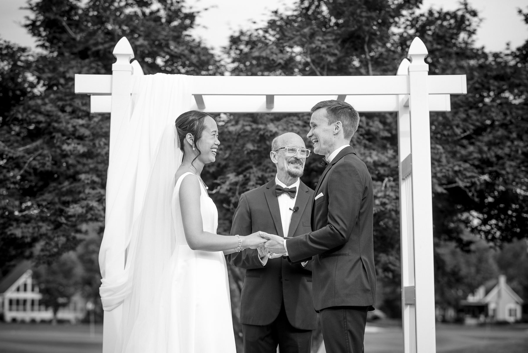 Bride and groom smile while exchanging vows during their outdoor wedding ceremony at Providence Country Club in Charlotte, NC, photographed by DeLong Photography. This timeless ceremony moment highlights the candid, emotional storytelling couples search for when looking for a Charlotte wedding photographer.
