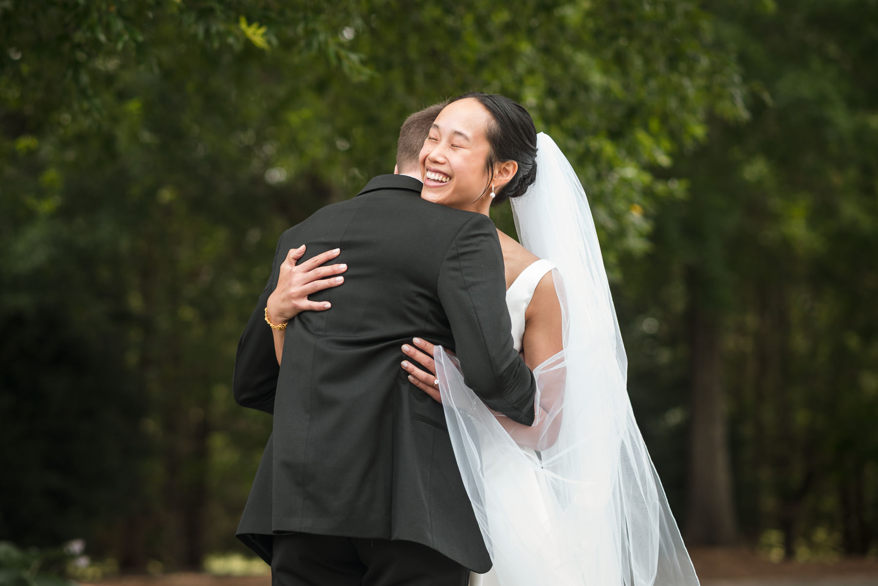 Bride and groom embracing and laughing during their first look at Providence Country Club, photographed by DeLong Photography, a Charlotte wedding photographer specializing in elegant country club weddings and candid wedding photography in Charlotte, NC.