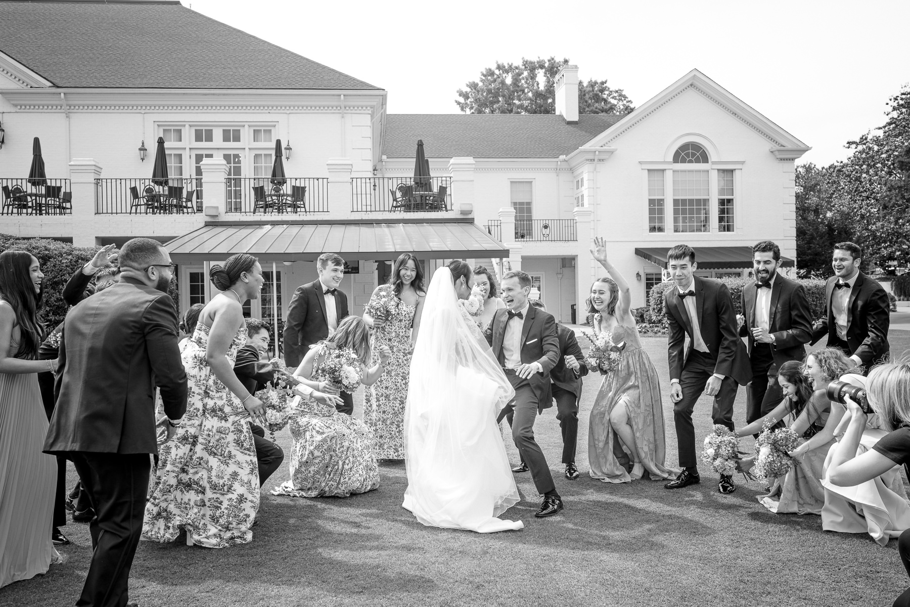 Bride and groom celebrate with their wedding party during fun wedding portraits at Providence Country Club in Charlotte, NC, photographed by DeLong Photography. This energetic and candid moment highlights the joyful storytelling and timeless imagery couples search for in a Charlotte wedding photographer.