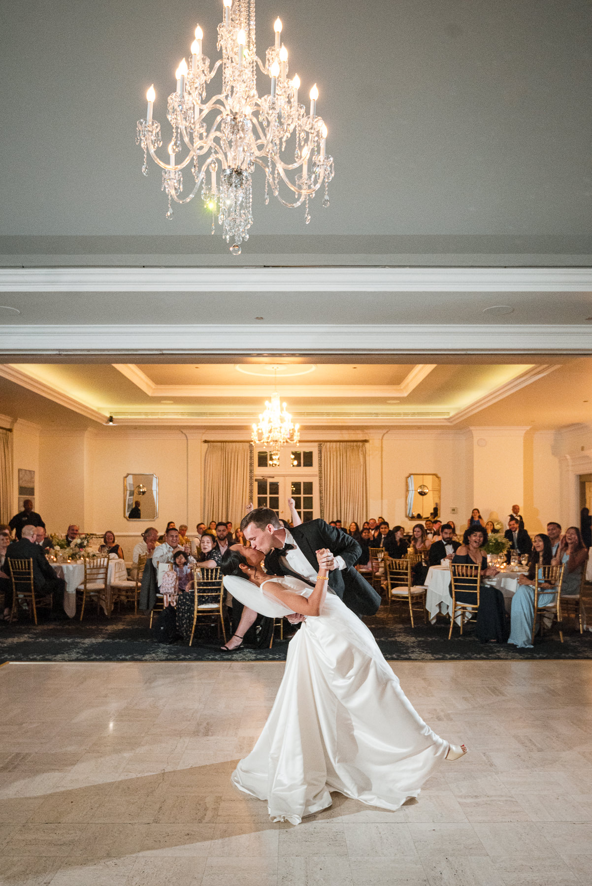 Bride and groom sharing their first dance and a dramatic dip kiss during their wedding reception at Providence Country Club, photographed by DeLong Photography, a Charlotte wedding photographer specializing in elegant ballroom receptions, candid moments, and timeless wedding photography in Charlotte, NC.