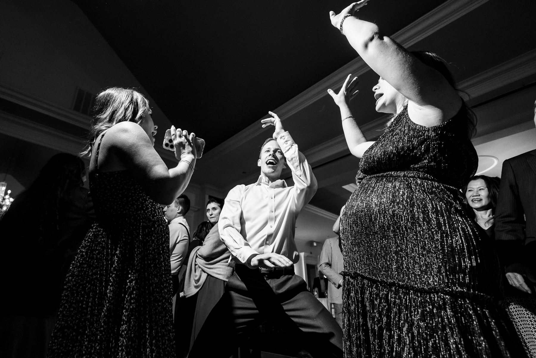 Wedding guests celebrate on the dance floor during a high-energy reception at Providence Country Club, photographed by DeLong Photography in Charlotte, NC. This candid black-and-white wedding reception photography captures the excitement and authentic moments couples look for when searching for Charlotte wedding photographers.