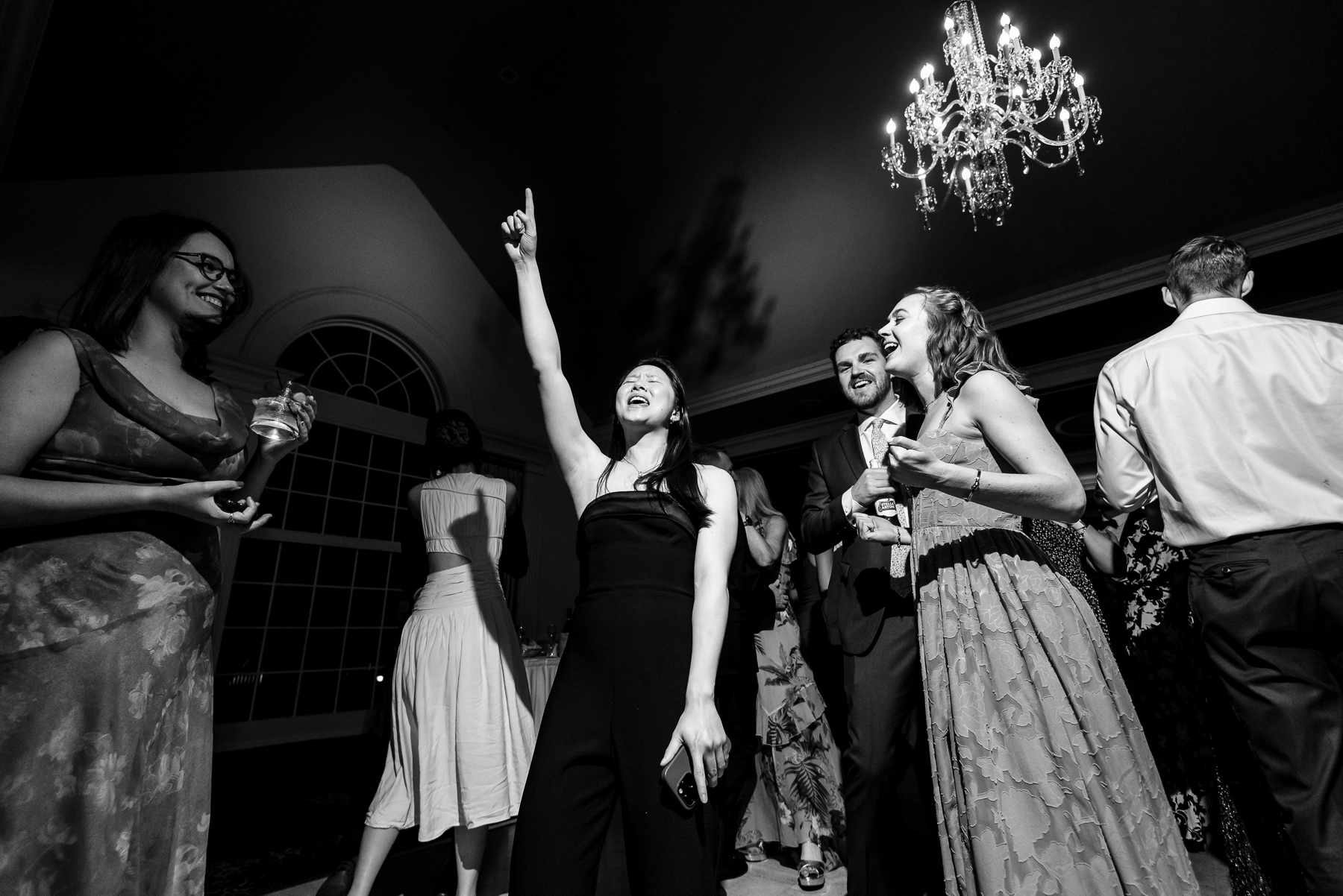 Guests dancing and singing during a lively wedding reception at Providence Country Club, photographed by DeLong Photography, a Charlotte wedding photographer specializing in candid wedding photography, energetic dance floor moments, and elegant country club weddings in Charlotte, NC.