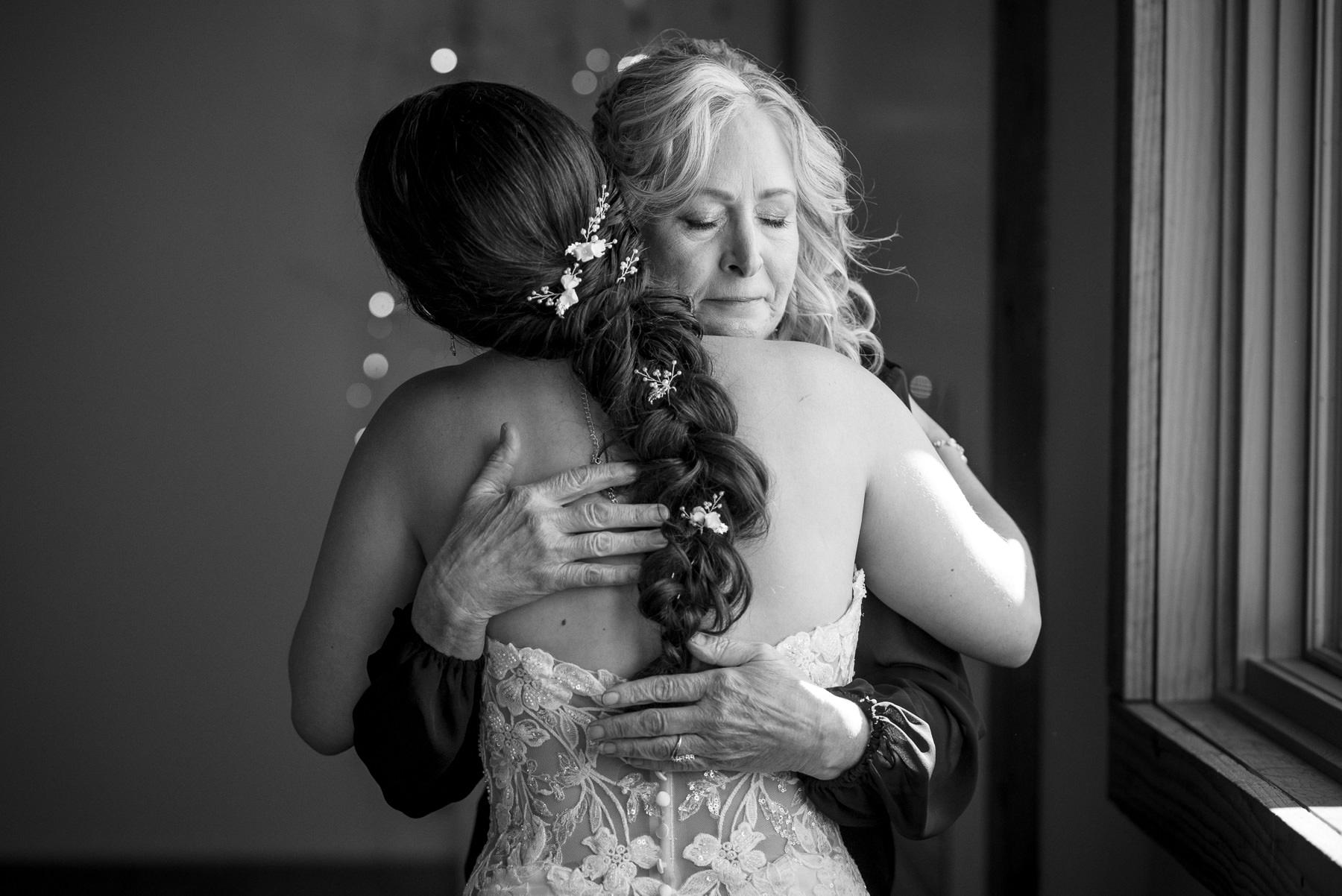 Emotional black and white photo of the bride sharing a heartfelt hug with her mother before the ceremony at a Camelot Meadows wedding in Charlotte, NC. Candid getting-ready moment captured by DeLong Photography, a Charlotte wedding photographer.