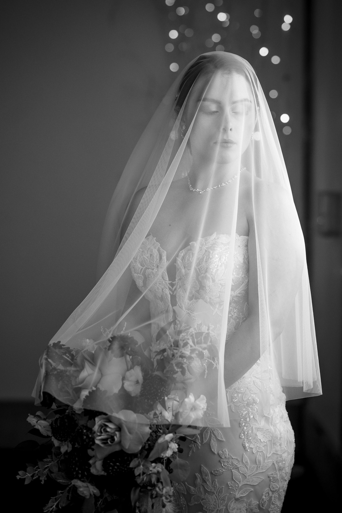 Black and white bridal portrait of the bride beneath her wedding veil while holding her bouquet before the ceremony at Camelot Meadows in Charlotte, NC. Timeless getting-ready photo captured by DeLong Photography, a Charlotte wedding photographer.